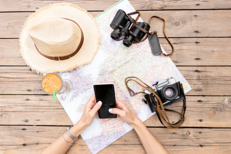 Planowanie urlopu – mapa, telefon i aparat fotograficzny na drewnianym stole