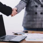 Dwie osoby podpisujące kontrakt. Umowa B2B praca zdalna i jej najważniejsze zapisy.